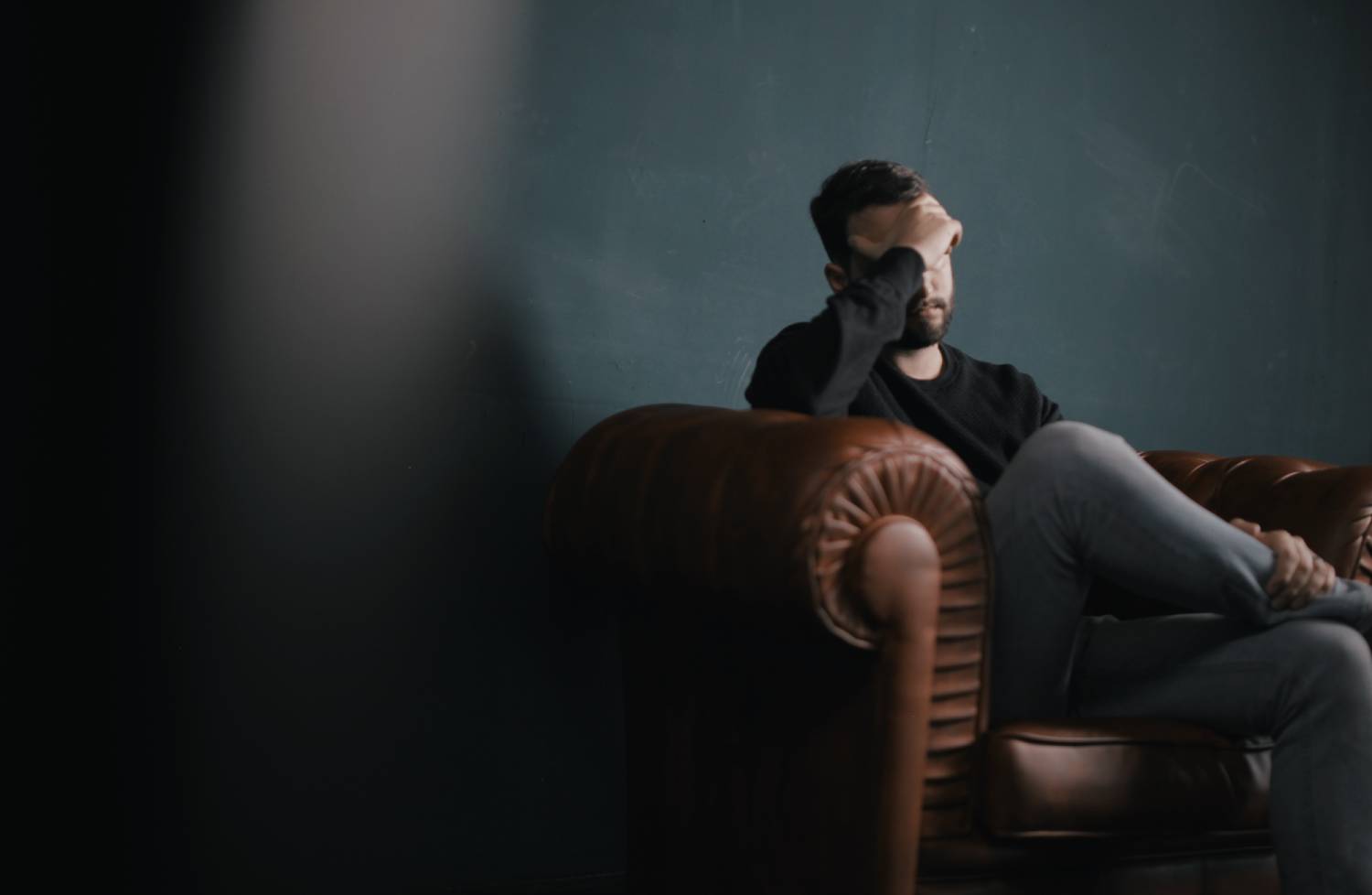 a man sitting on top of a brown leather couch