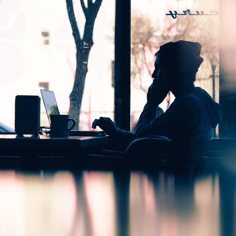 a person sitting at a table with a laptop