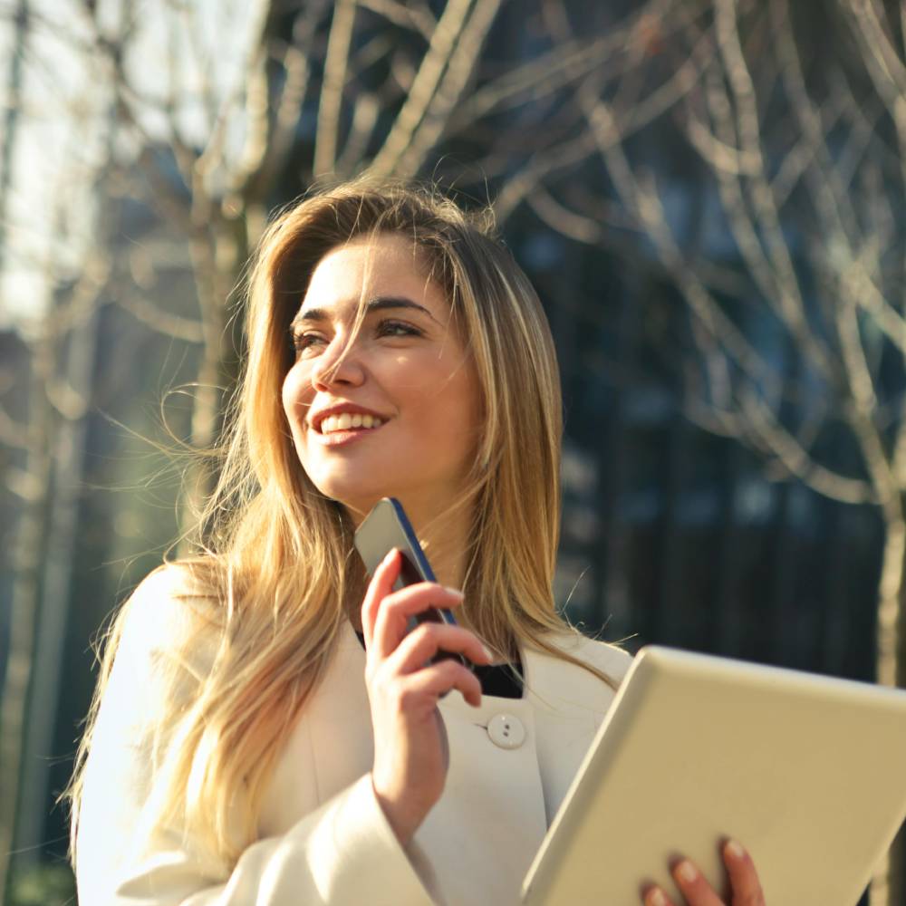 woman-wearing-white-top-holding-smartphone-and-tablet