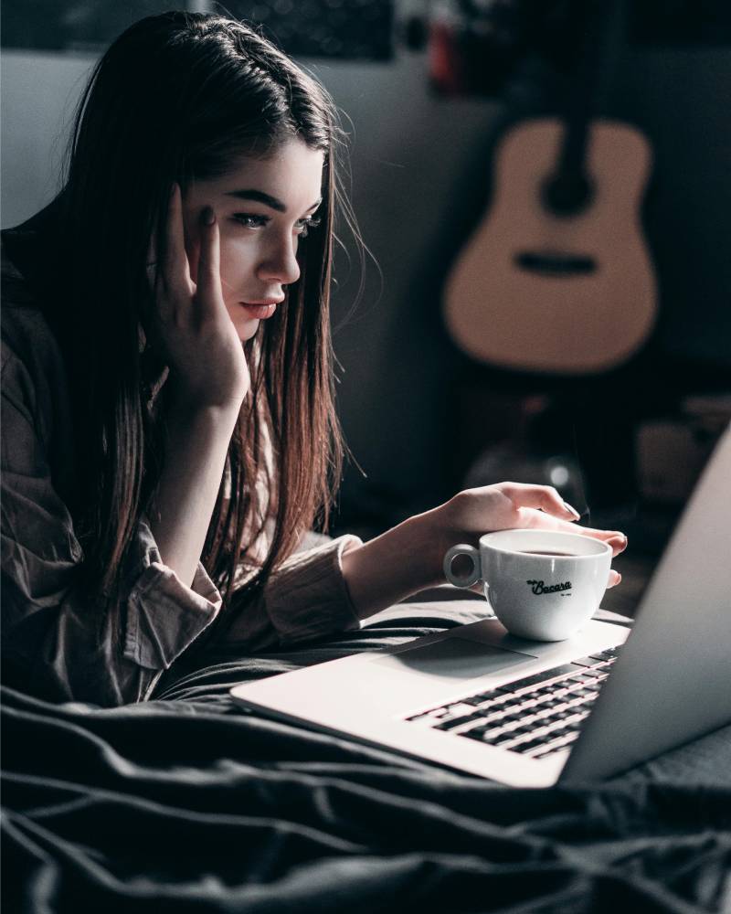 woman-lying-on-bed-while-using-laptop